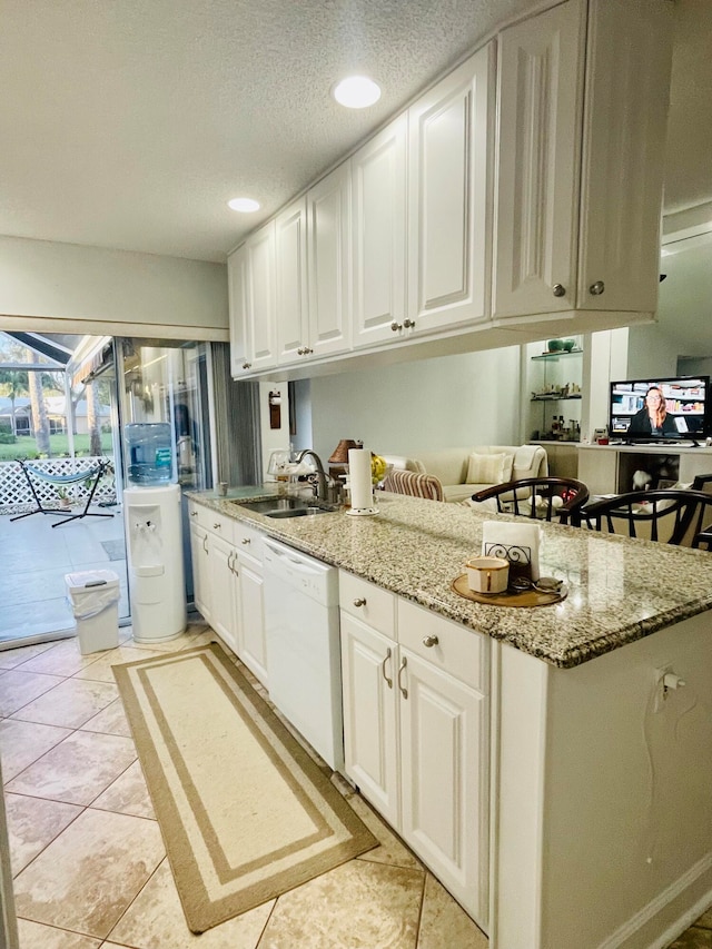 kitchen featuring light stone countertops, white cabinetry, sink, and dishwasher