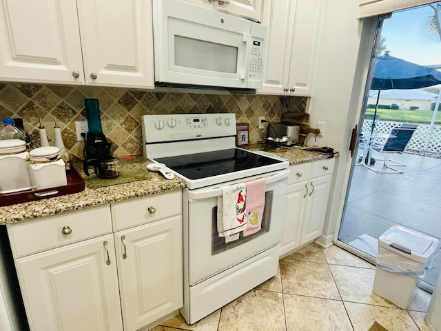 kitchen featuring light stone counters, light tile patterned flooring, white cabinetry, backsplash, and white appliances