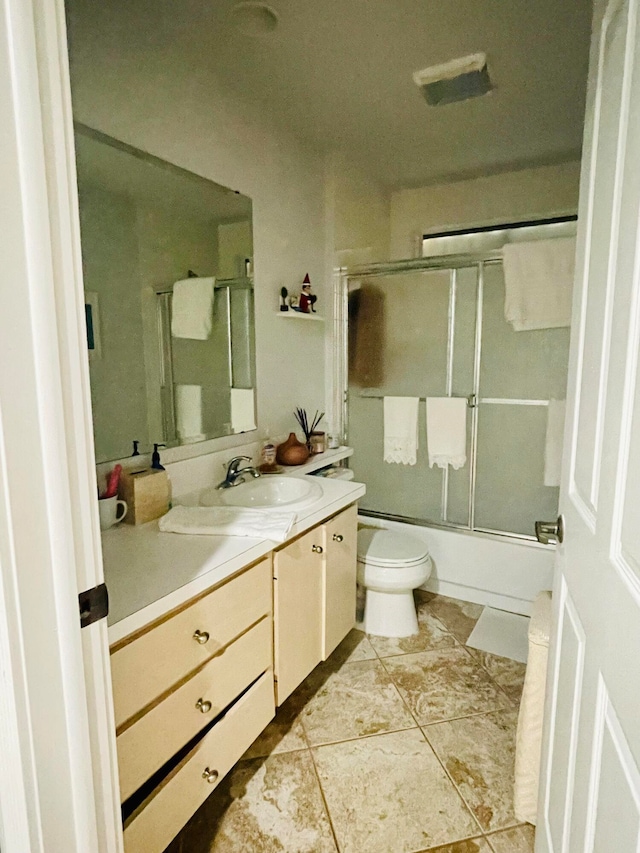 full bathroom featuring tile patterned flooring, vanity, combined bath / shower with glass door, and toilet