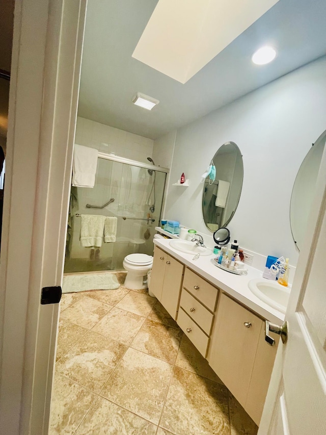 bathroom with toilet, tile patterned flooring, an enclosed shower, vanity, and a skylight