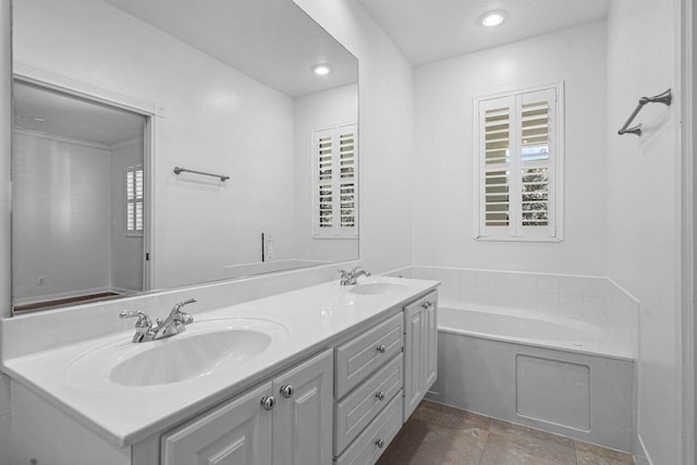 full bathroom with recessed lighting, a garden tub, a sink, and double vanity