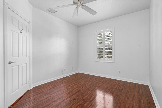 unfurnished room featuring ceiling fan, dark wood finished floors, visible vents, and baseboards