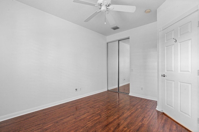 unfurnished bedroom with dark wood-style floors, ceiling fan, baseboards, and a closet