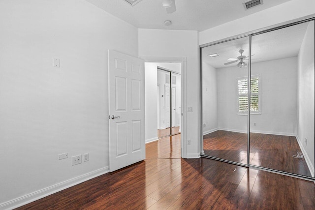 unfurnished bedroom with a closet, wood finished floors, visible vents, and baseboards