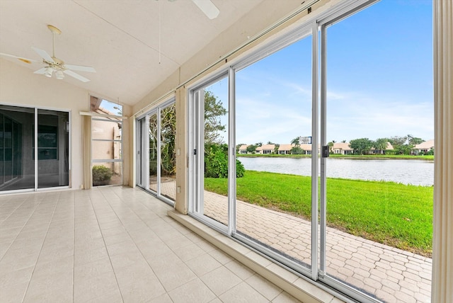 unfurnished sunroom featuring a water view, a healthy amount of sunlight, ceiling fan, and vaulted ceiling