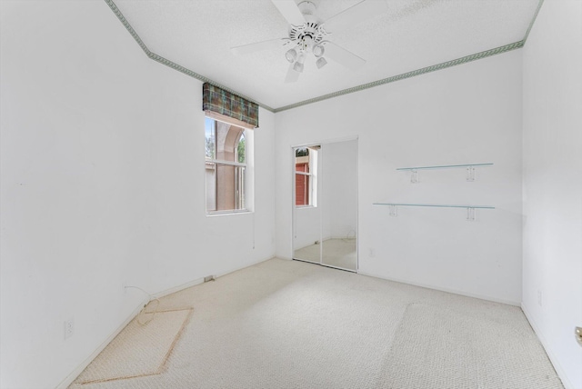 spare room with ceiling fan, crown molding, a textured ceiling, and carpet floors