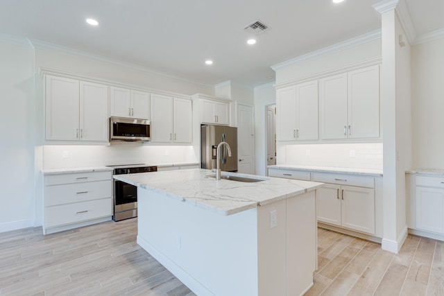 kitchen with white cabinetry, sink, light stone counters, appliances with stainless steel finishes, and a kitchen island with sink