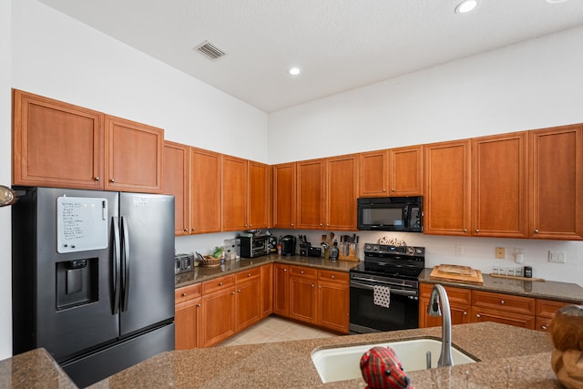 kitchen featuring sink, dark stone countertops, light tile patterned floors, and stainless steel appliances