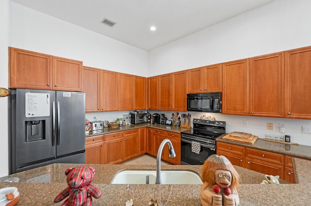 kitchen featuring light stone countertops, sink, and black appliances