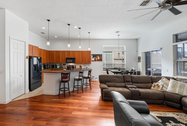 living room with a textured ceiling, dark hardwood / wood-style floors, and ceiling fan with notable chandelier