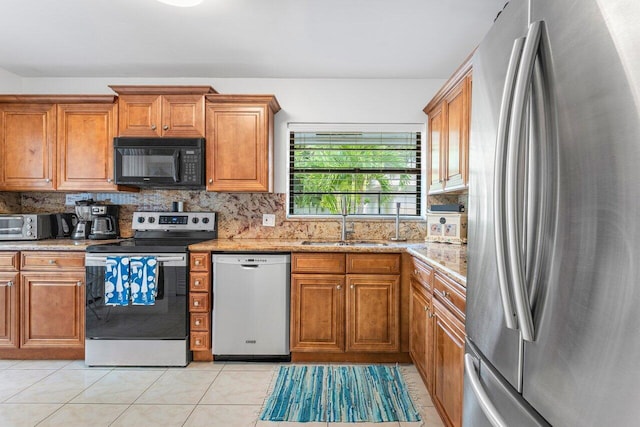 kitchen with decorative backsplash, light stone counters, sink, and appliances with stainless steel finishes