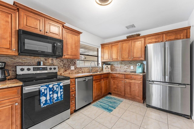 kitchen featuring light stone counters, sink, light tile patterned floors, and appliances with stainless steel finishes