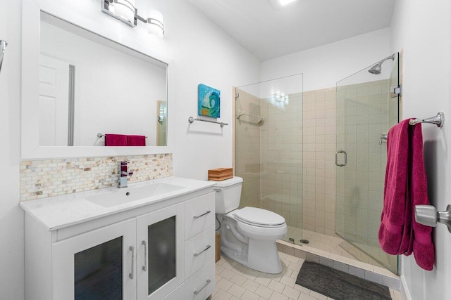 bathroom featuring backsplash, tile patterned floors, toilet, a shower with door, and vanity