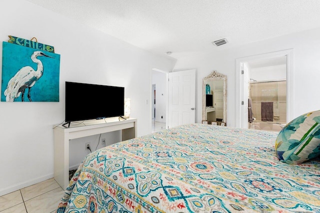 bedroom featuring light tile patterned floors, a textured ceiling, and ensuite bath