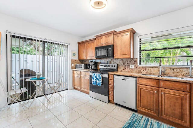 kitchen with sink, plenty of natural light, light stone countertops, and appliances with stainless steel finishes