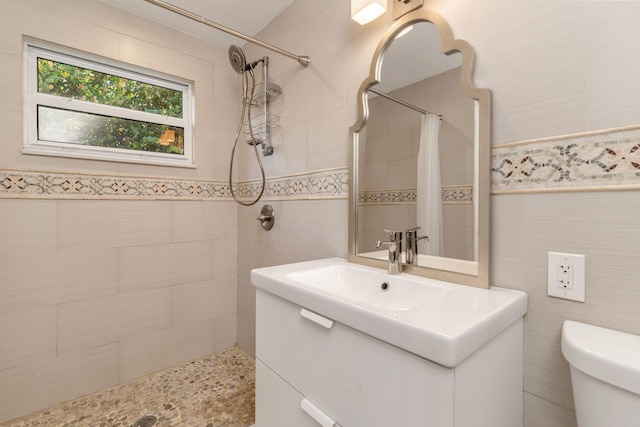 bathroom featuring walk in shower, vanity, tile walls, and toilet