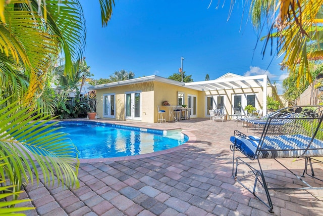 view of pool featuring a patio area, french doors, and exterior bar