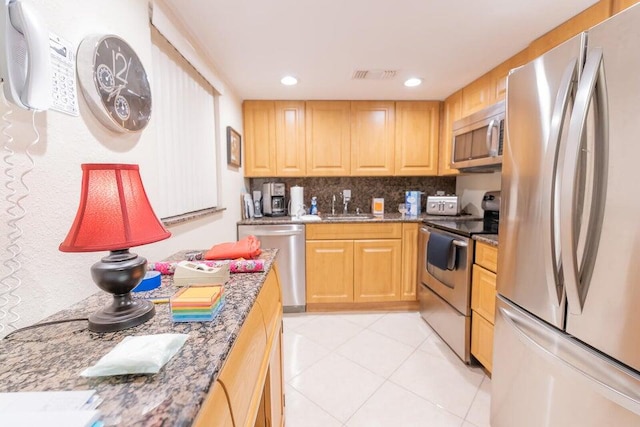 kitchen with decorative backsplash, appliances with stainless steel finishes, sink, and stone countertops