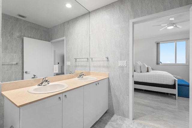 bathroom featuring ceiling fan, vanity, and tile walls