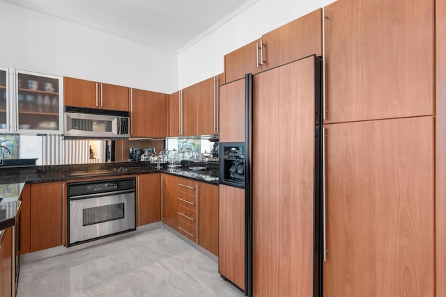 kitchen featuring stainless steel appliances, crown molding, and dark stone counters