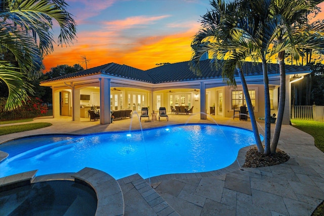 pool at dusk with ceiling fan, a patio, outdoor lounge area, and fence