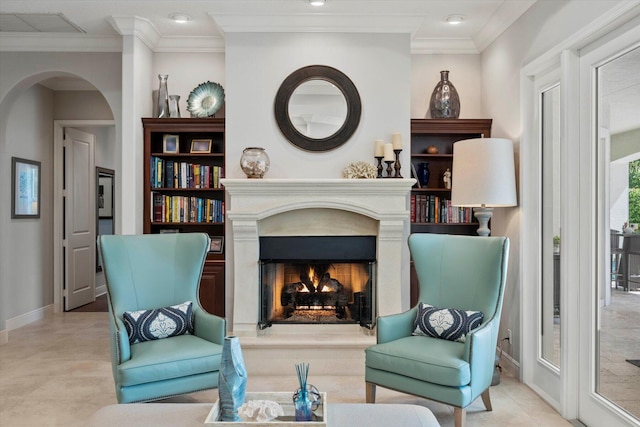 living area featuring a warm lit fireplace, baseboards, ornamental molding, and arched walkways