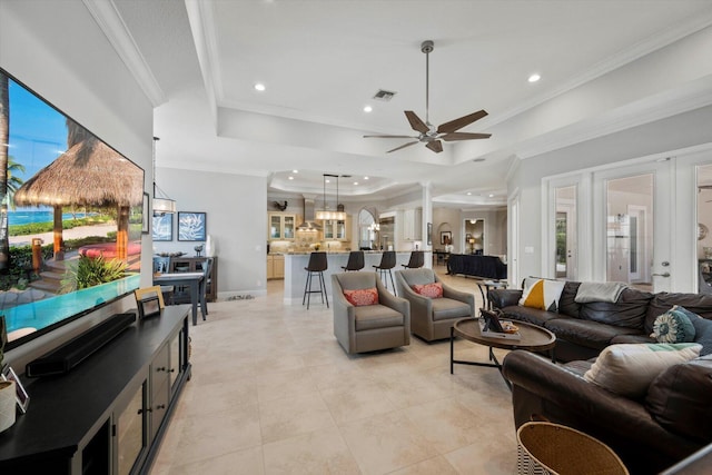 living area with a tray ceiling, visible vents, crown molding, and recessed lighting