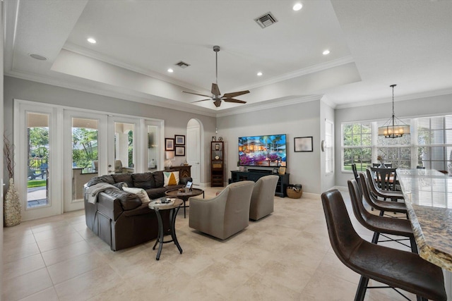 living room featuring arched walkways, ornamental molding, a raised ceiling, and visible vents