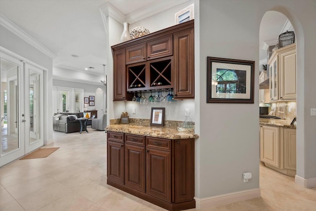 bar featuring arched walkways, french doors, ornamental molding, a bar, and baseboards