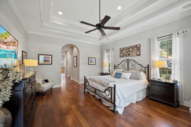 bedroom featuring baseboards, a tray ceiling, arched walkways, and dark wood-type flooring