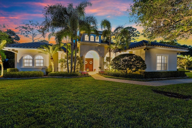 mediterranean / spanish home with stucco siding, decorative driveway, and a front yard