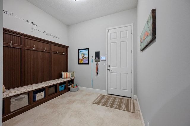 mudroom featuring a textured ceiling and baseboards