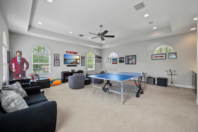 recreation room with ceiling fan, light carpet, and a tray ceiling