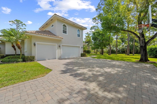 view of front of house featuring a front yard, decorative driveway, a tile roof, and stucco siding