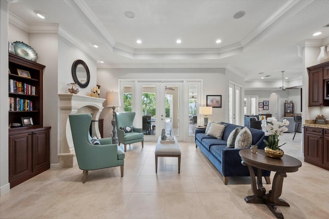 living area with light tile patterned floors, a premium fireplace, ornamental molding, french doors, and a raised ceiling