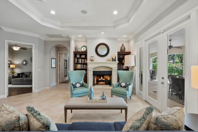living area featuring a tray ceiling, crown molding, and arched walkways