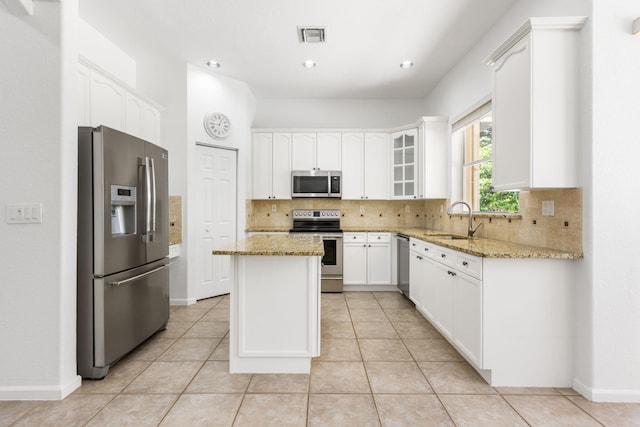 kitchen with stainless steel appliances, sink, a kitchen island, and light stone countertops