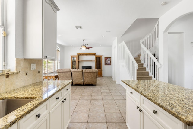 kitchen with backsplash, light stone counters, and white cabinets