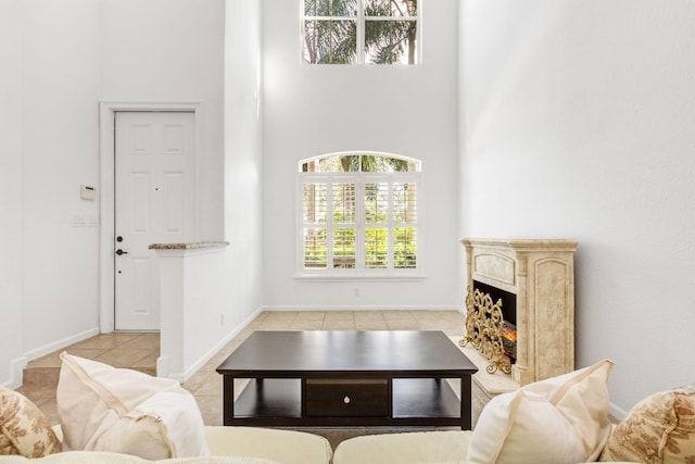 living room with a healthy amount of sunlight, a high ceiling, a high end fireplace, and light tile patterned floors