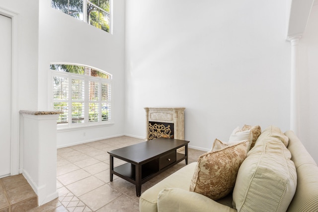 tiled living room with a high ceiling and decorative columns