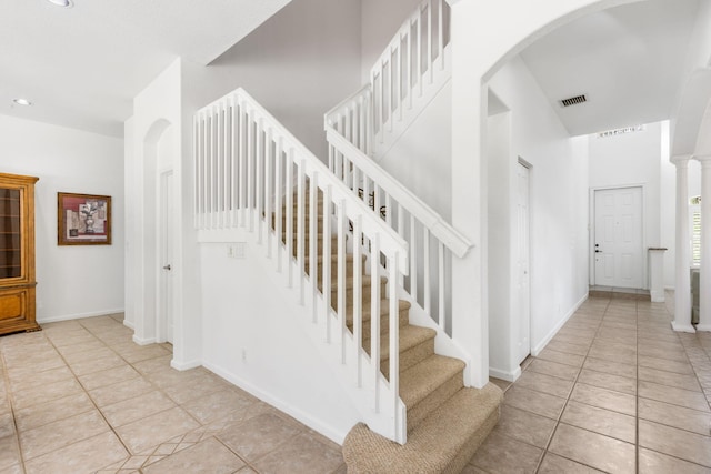 stairway featuring tile patterned floors and decorative columns