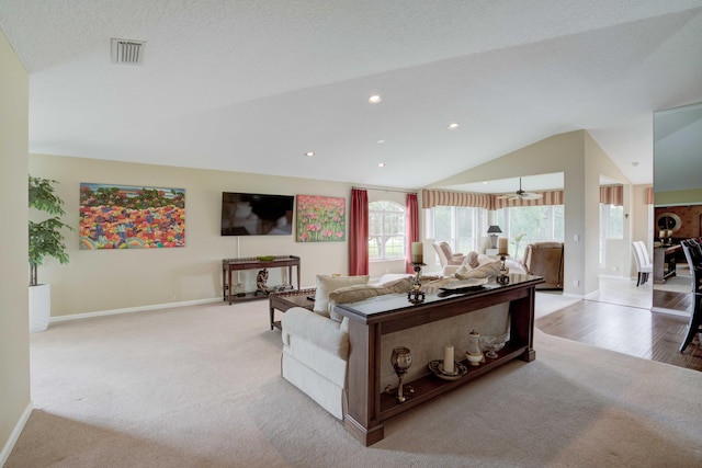 living room with light hardwood / wood-style flooring, a textured ceiling, and vaulted ceiling