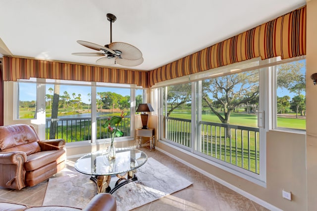 sunroom featuring ceiling fan and a water view