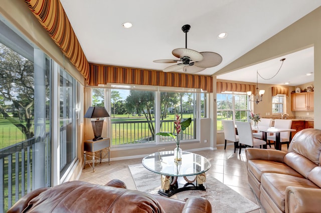 sunroom featuring ceiling fan with notable chandelier and vaulted ceiling