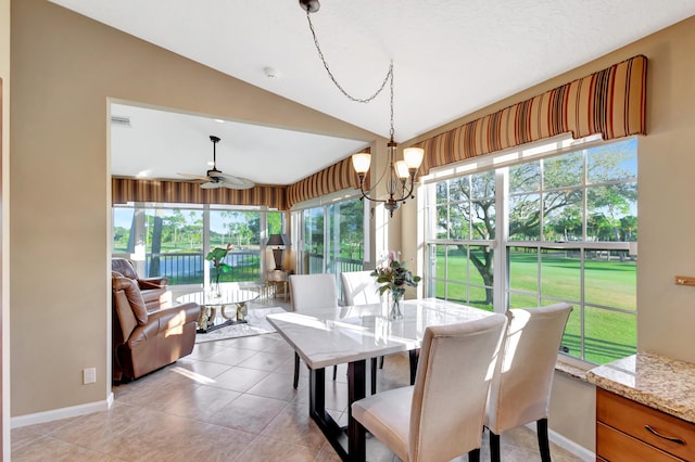 dining area featuring ceiling fan with notable chandelier, a healthy amount of sunlight, vaulted ceiling, and light tile patterned floors