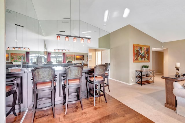 227 Legendary Cir, Palm Beach Gardens, FL 33418 - kitchen with a kitchen bar, baseboards, light wood-type flooring, high vaulted ceiling, and light colored carpet