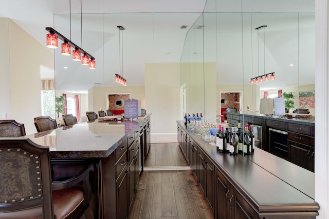 kitchen featuring dark brown cabinets, a kitchen bar, a large island, and dark hardwood / wood-style flooring