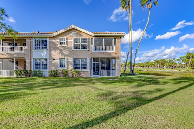 227 Legendary Cir, Palm Beach Gardens, FL 33418 - rear view of house with stucco siding, a sunroom, a lawn, and a tiled roof