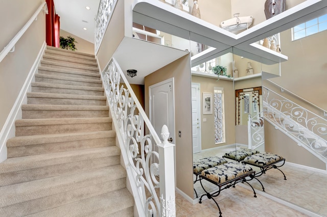 stairs featuring tile patterned flooring and a towering ceiling