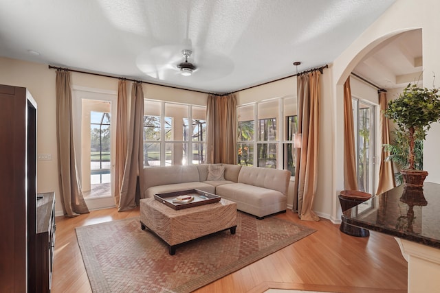 living room featuring light hardwood / wood-style flooring, a textured ceiling, and ceiling fan